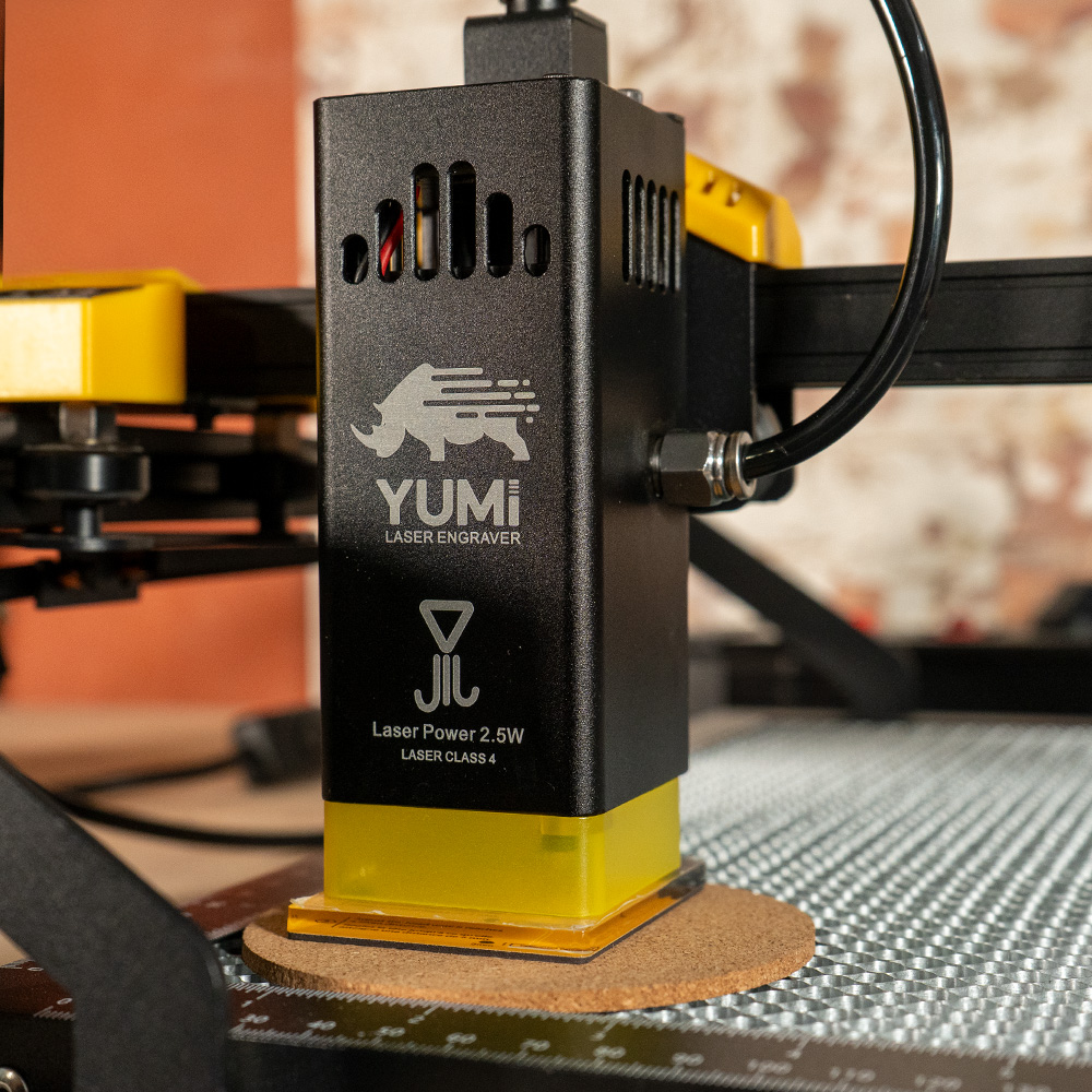 Yumi L-A4 laser head positioned over a cork disc on the honeycomb bed for height adjustment